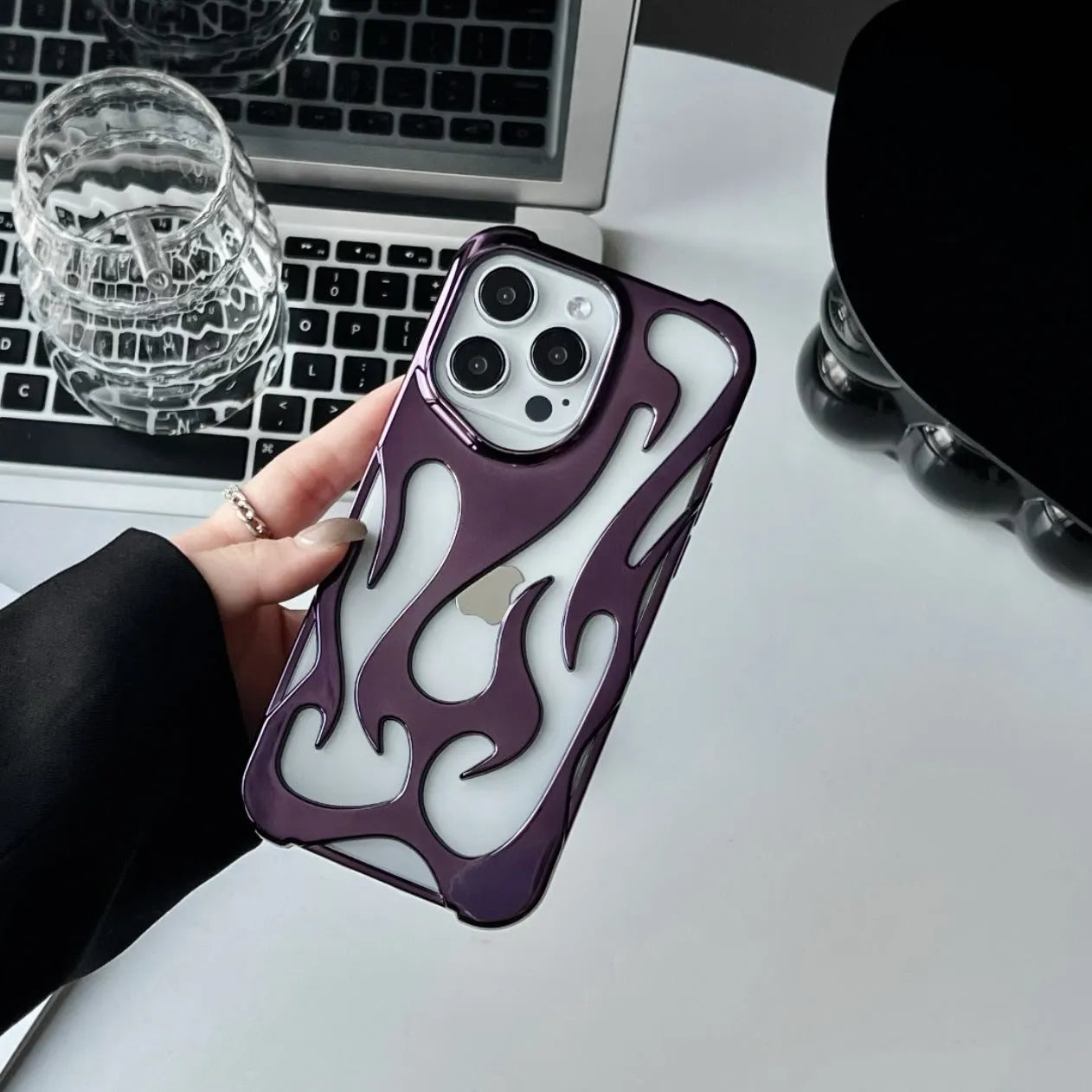 Apple iPhone case with hollow flame pattern and electroplated finish in silver, shown on a phone.