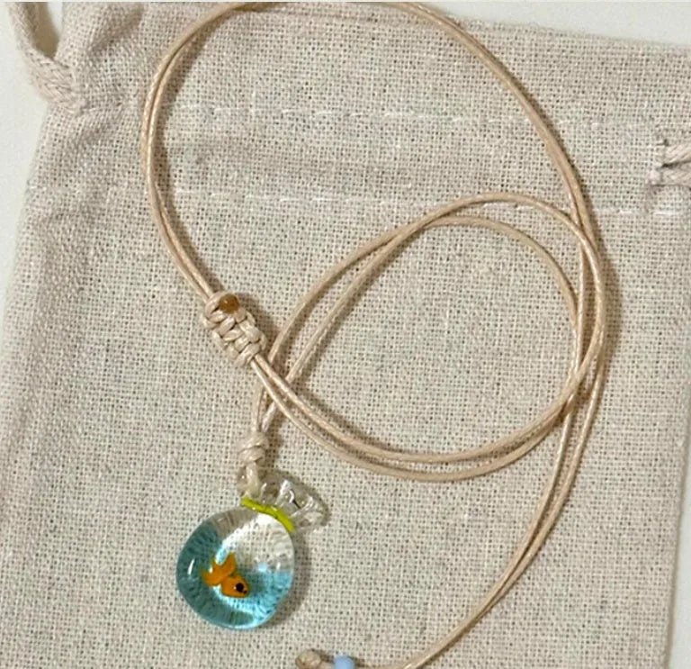 Women's necklace with coloured glaze joker pendant on a woven cotton and linen clavicle chain.