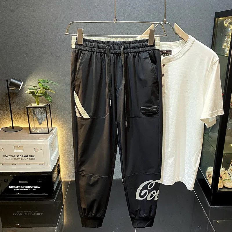 Men's black ice silk ankle banded cropped casual trousers on a plain background.