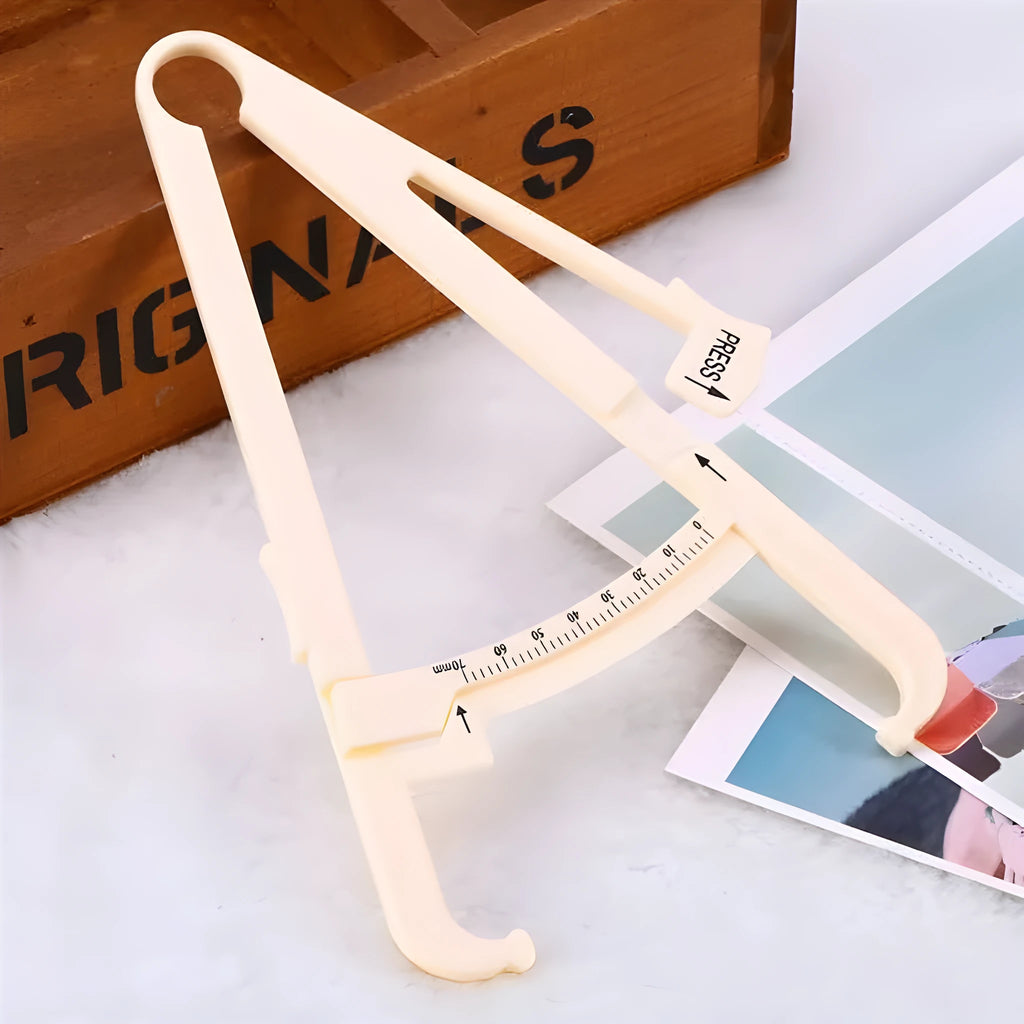 Clear acrylic body fat caliper skin fold thickness meter showing measurement scale