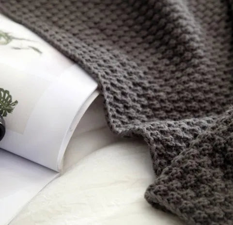 Nordic fringed knit ball acrylic blanket in beige, measuring 130 by 170 cm on a sofa.