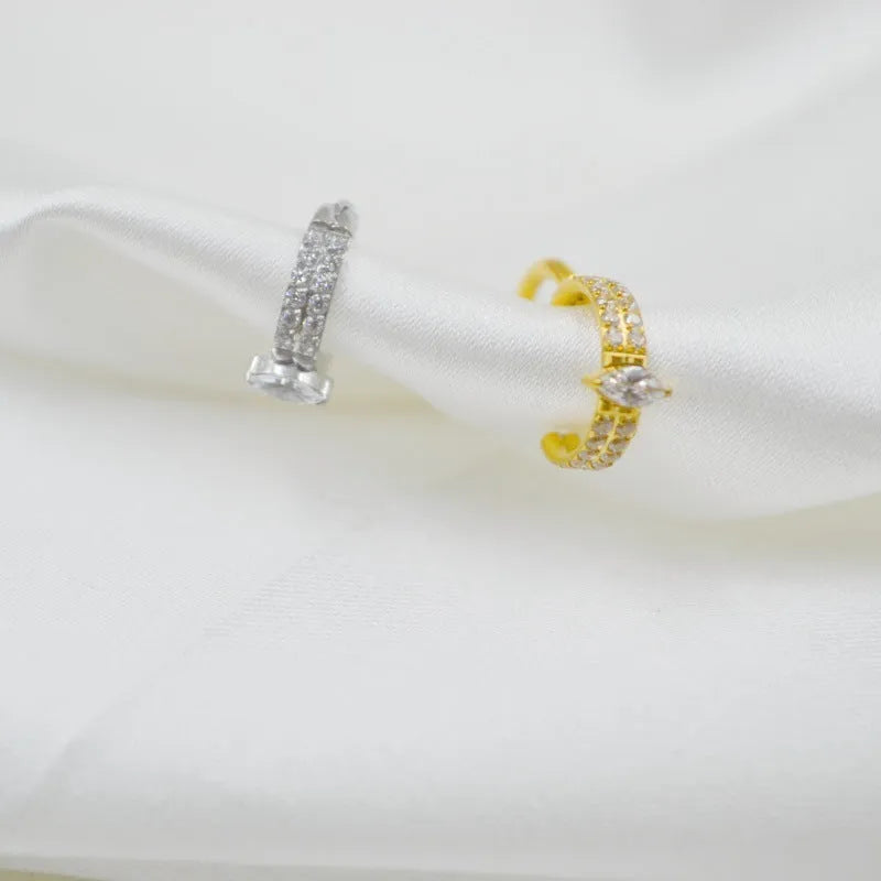 Close-up of a silver heart shaped titanium steel earring with a small zircon stone.