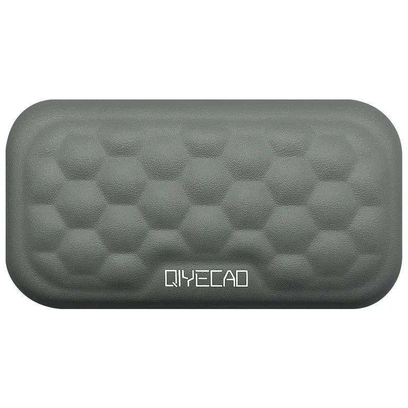 Black memory foam mouse wrist pad with silicone bottom on a wooden desk