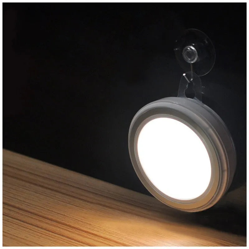 Wireless round motion sensor LED light with white plastic housing, shown mounted inside a wardrobe.