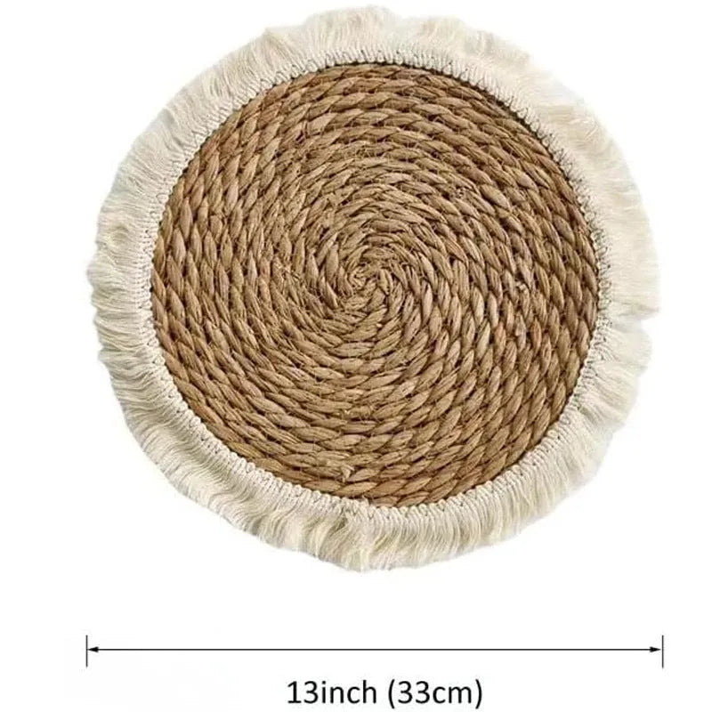 Round natural papyrus straw placemat with tassel edge on a wooden table.