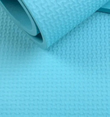 EVA fitness yoga mat in blue, showing its texture and thickness, rolled up with its OPP storage bag.