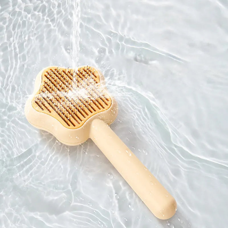 Green self-cleaning stainless steel pet comb with removable needle head on a white background.