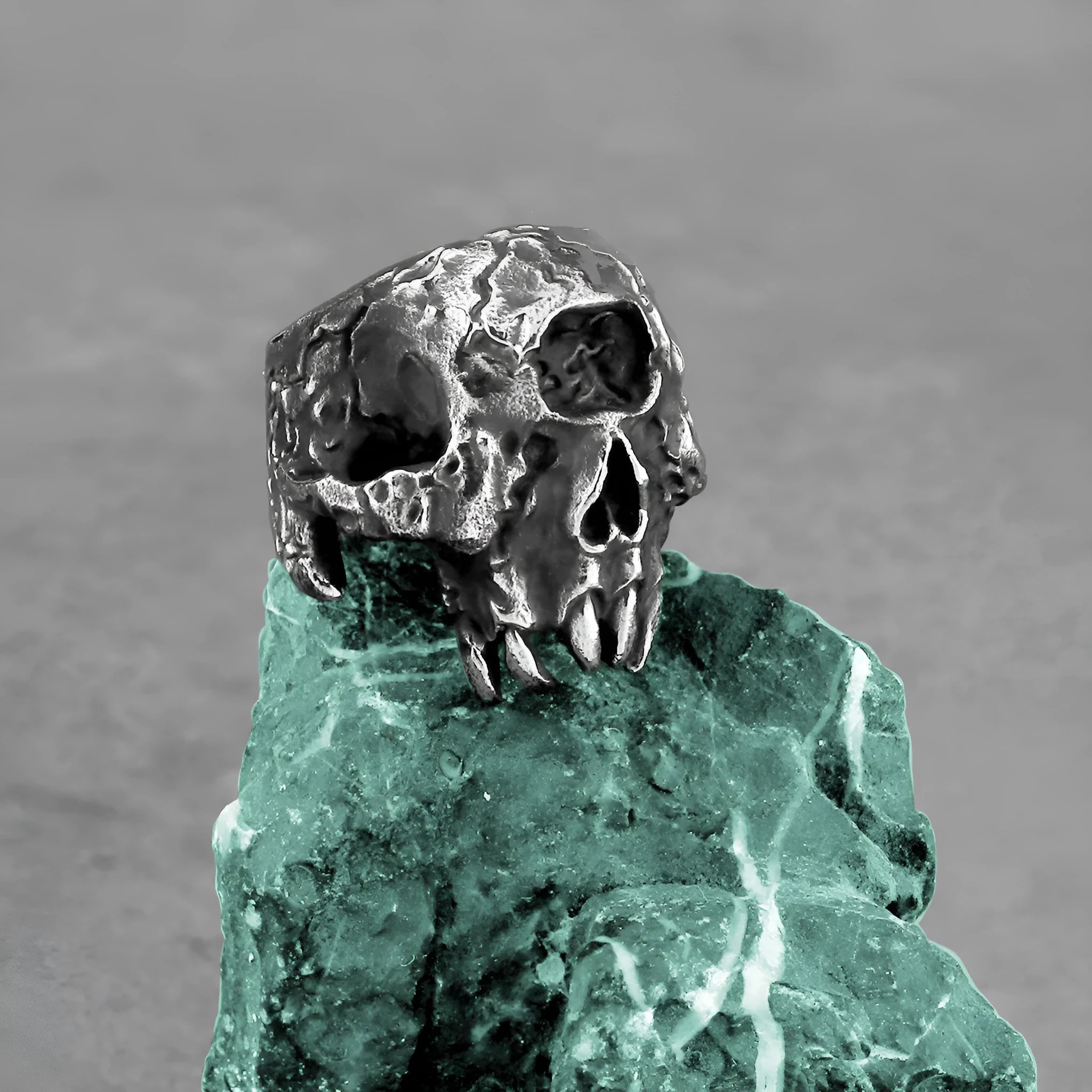 Close-up of a retro alloy ring with a detailed one-eyed skull design on a dark background.