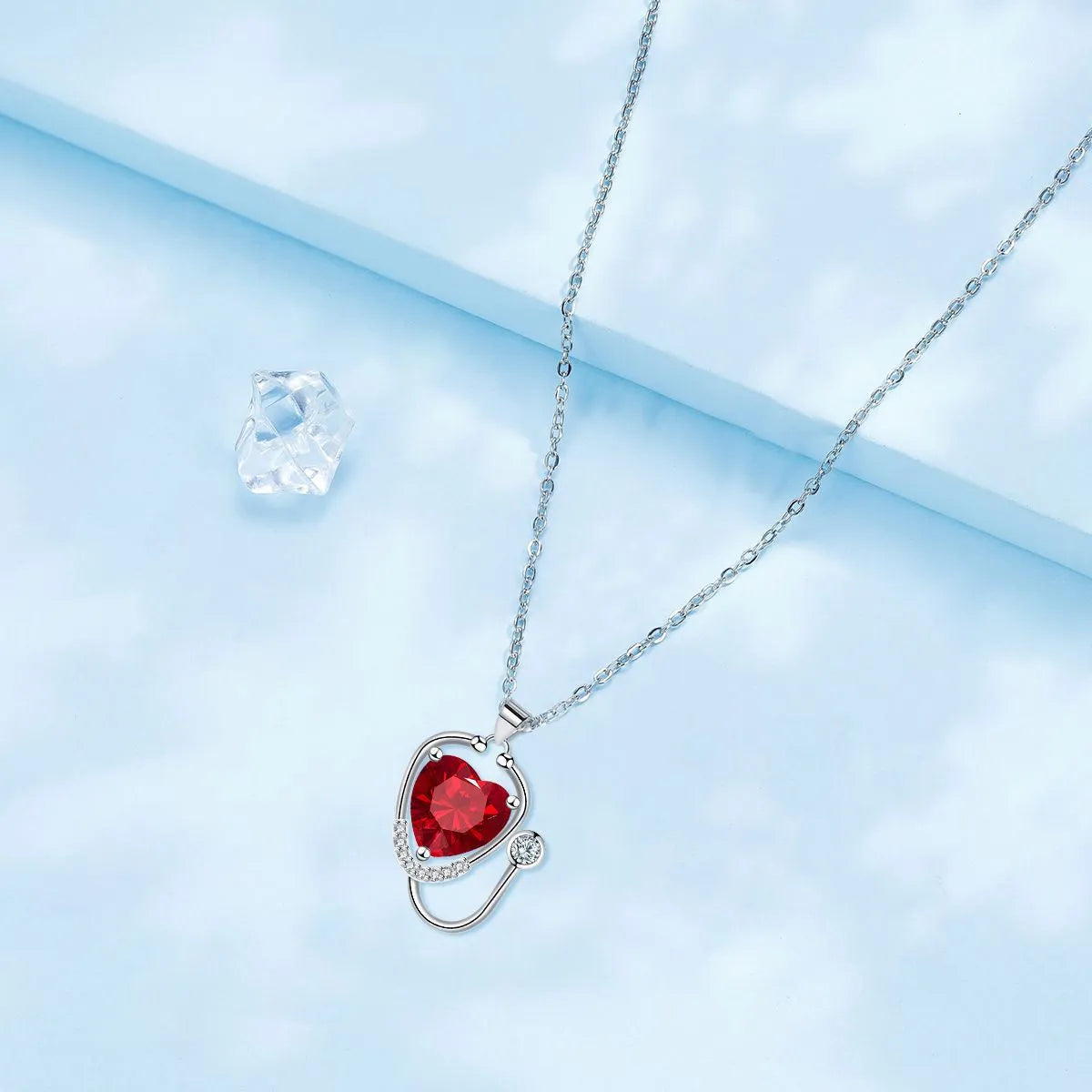 Red diamond copper necklace with stethoscope-shaped pendant featuring wings and cross detailing