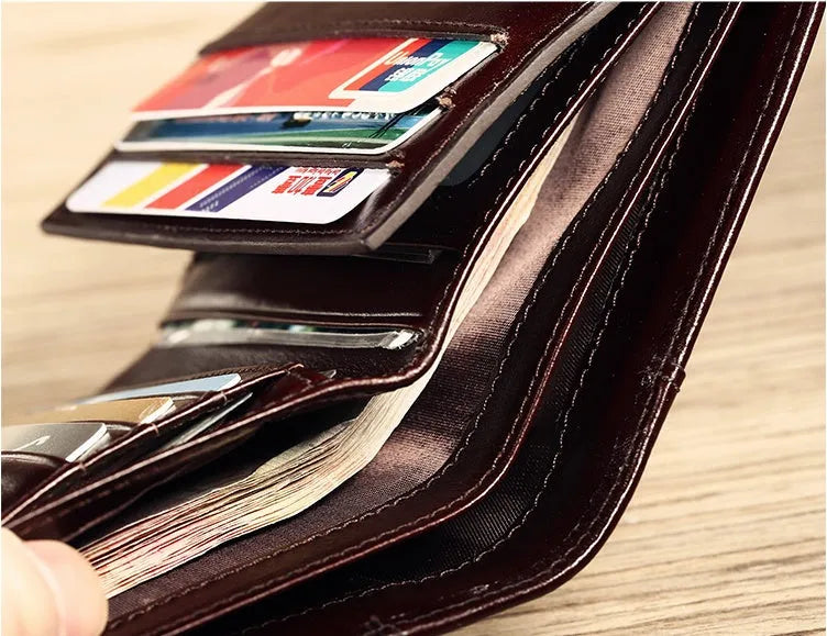 Men's brown leather bifold wallet open to show internal card slots, coin pocket, and photo holder.