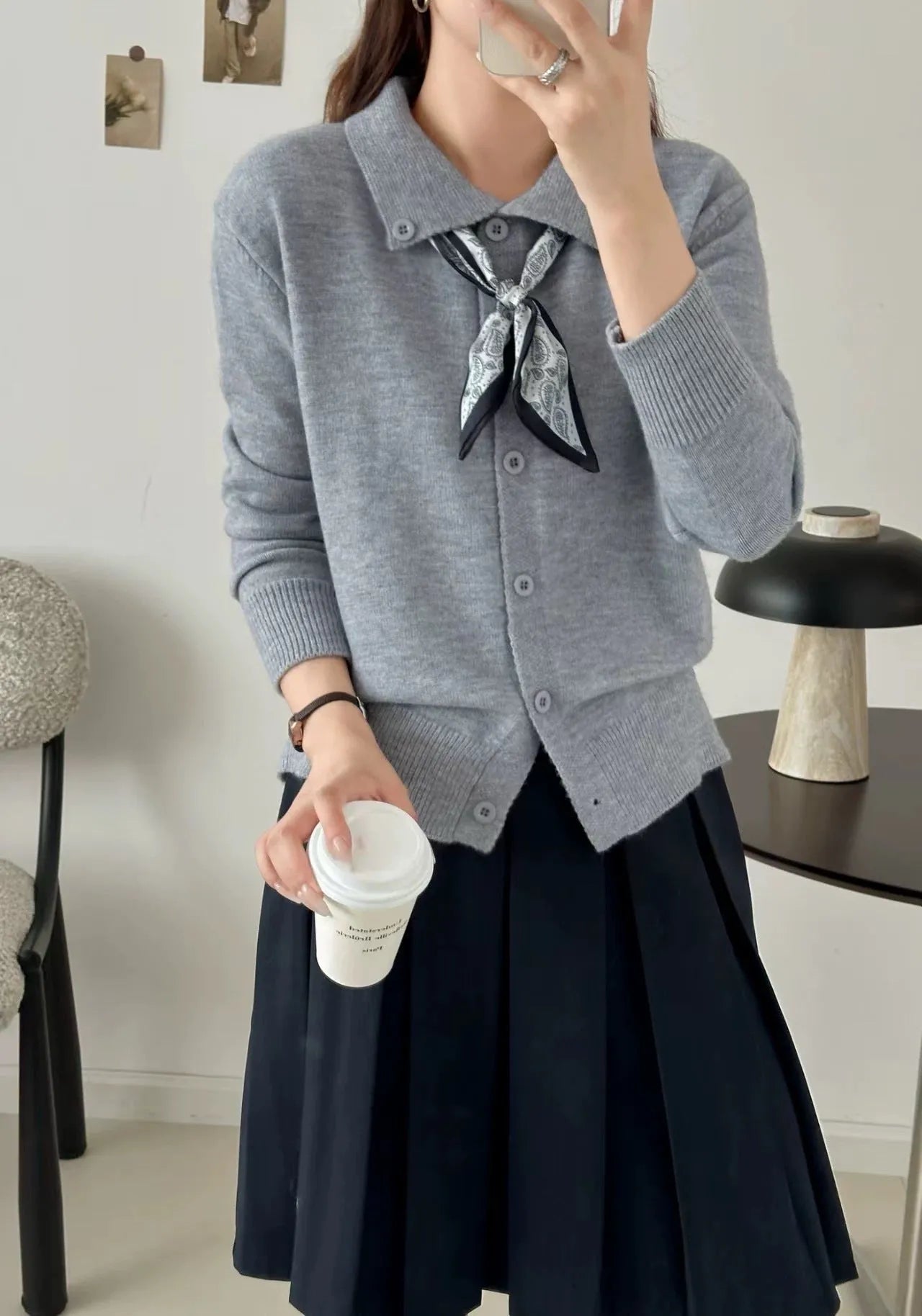 Beige acrylic cardigan with lapel scarf collar and splicing detail on a hanger.