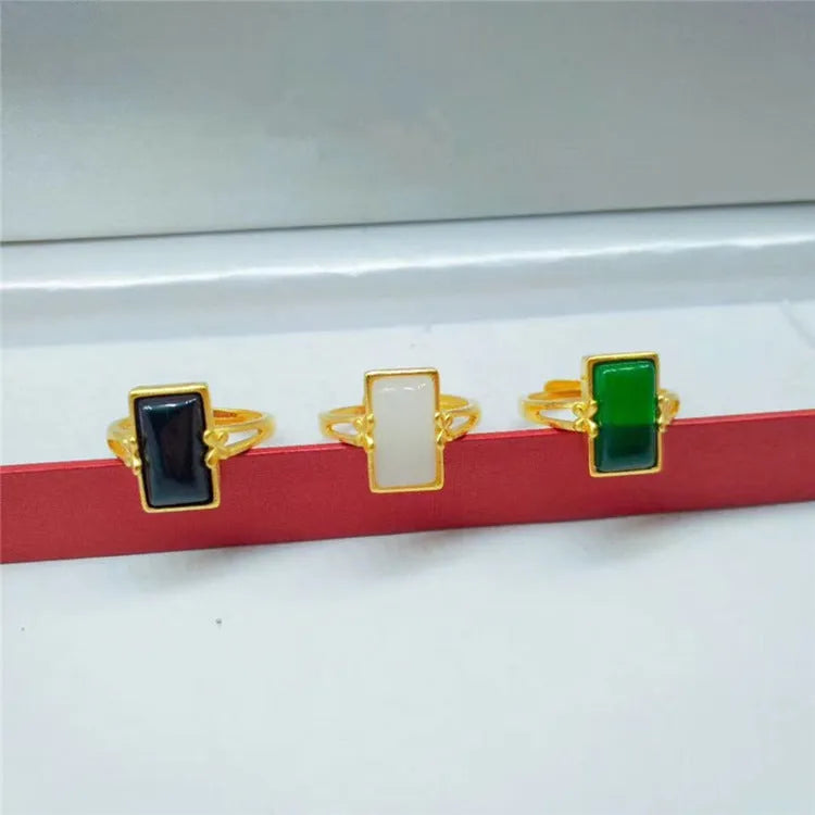 Adjustable brass gold-plated ring with a long black gemstone inlay on a finger.