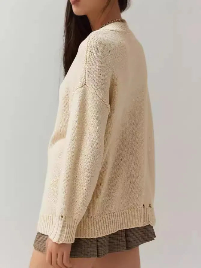 Women's milky white acrylic round neck sweater with jacquard long sleeves, laid flat.