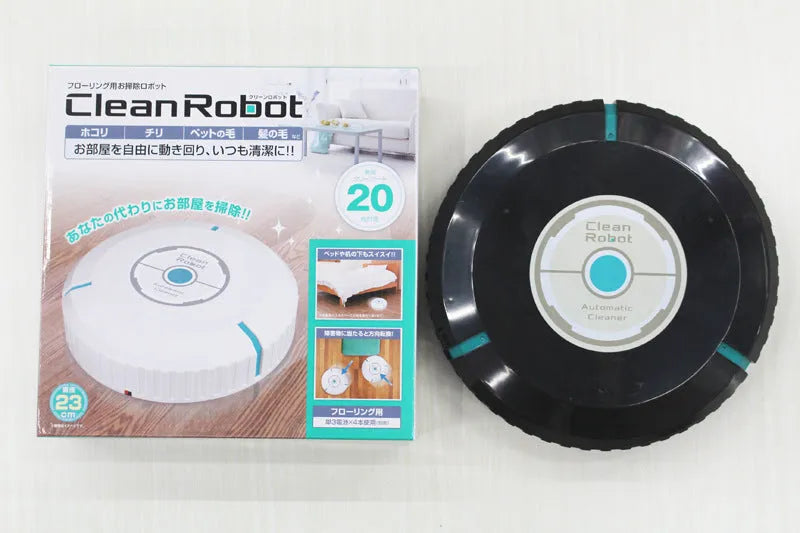 Compact black and white robot vacuum cleaner on a wooden floor