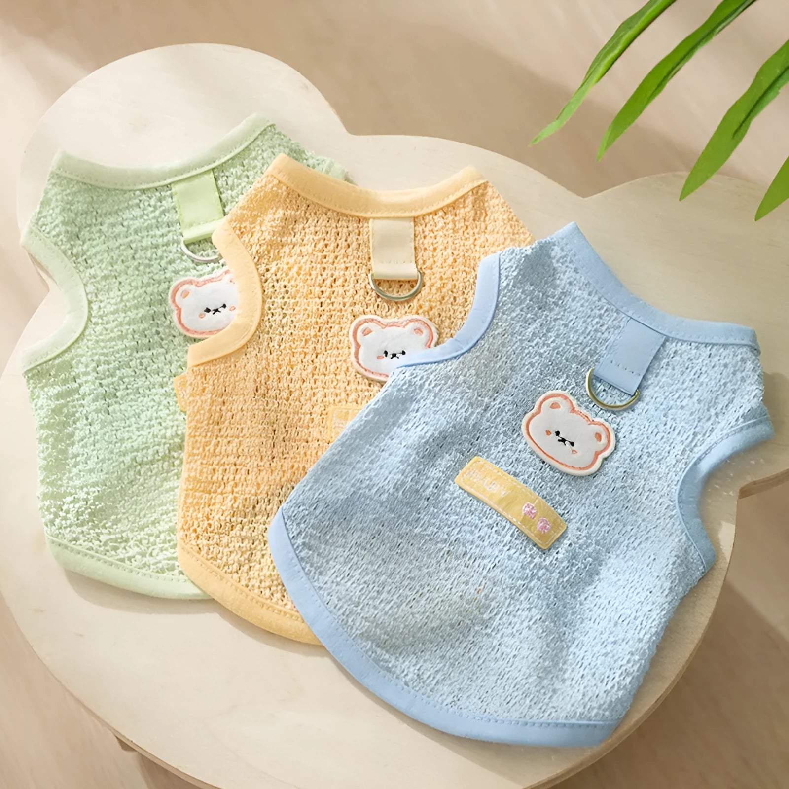 Green knitted cat clothing with bear patch design showing hollowed-out breathable fabric construction