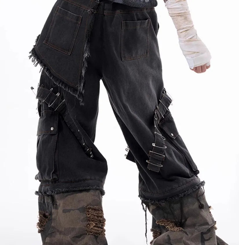 Grey men's jeans with camouflage pattern splicing and silver pin and black ribbon detailing on the legs.