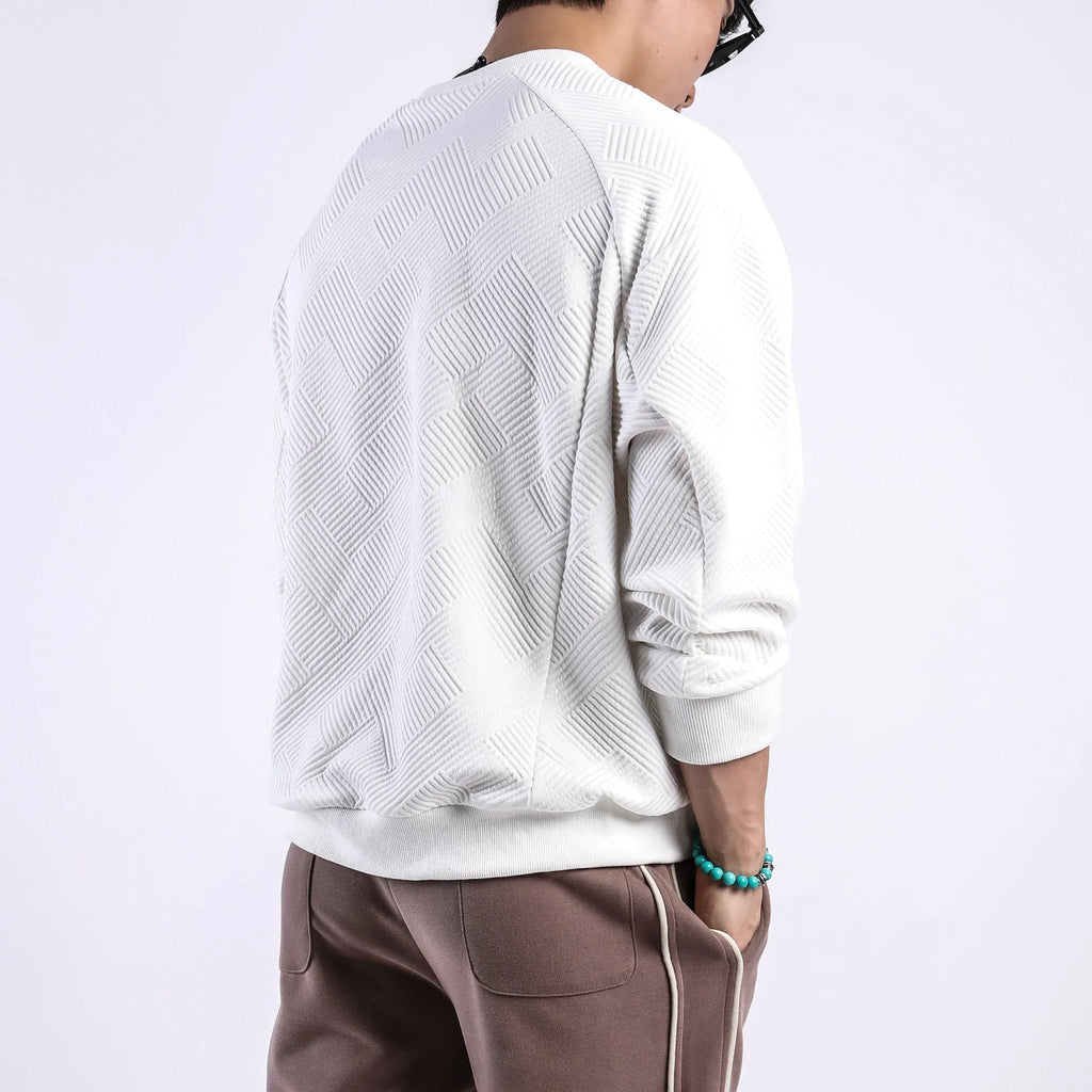 Man wearing a loose-fit, long-sleeved twill jacquard sweater in a solid colour with a round neck.