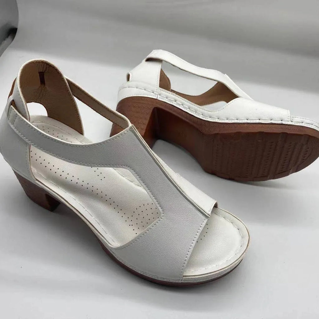 Women's beige peep toe wedge sandals with an adjustable ankle buckle strap on a foot.