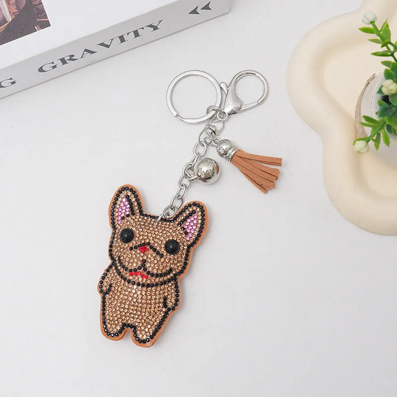 Close-up of a French dog style cartoon bear rhinestone keychain charm on a keyring.