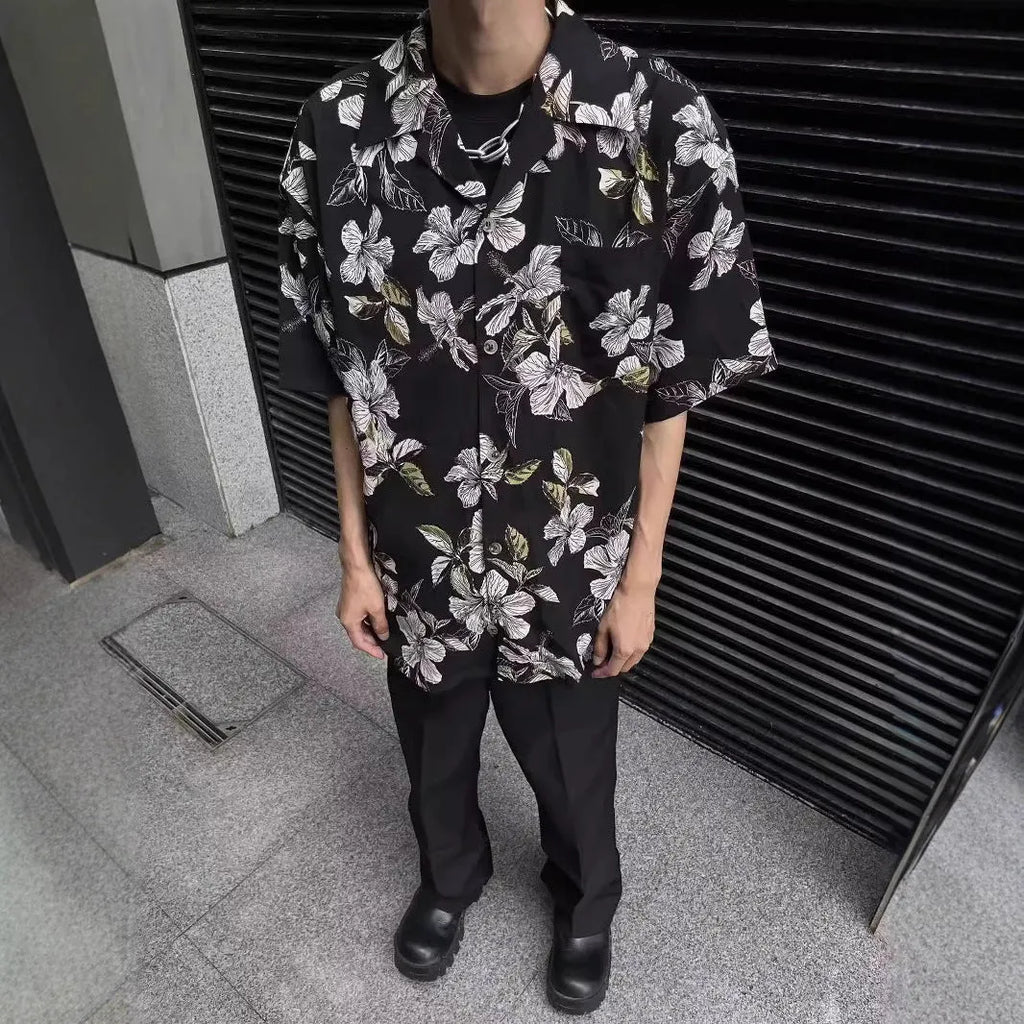 Man wearing a black ice silk shirt with floral print, Cuban collar, and short sleeves.