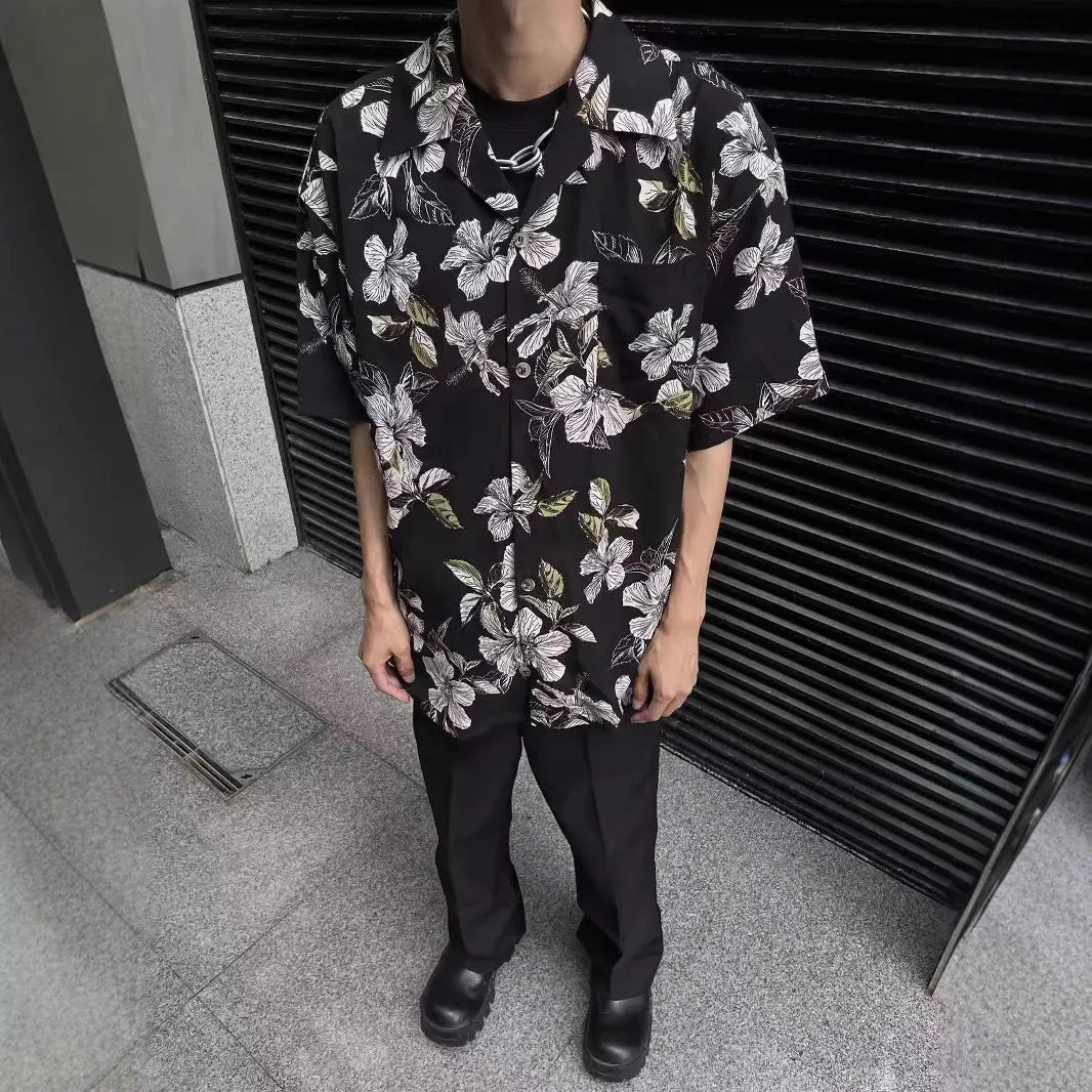 Man wearing a black ice silk shirt with floral print, Cuban collar, and short sleeves.