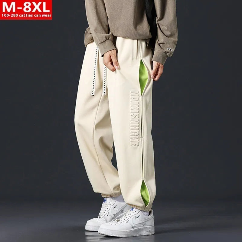 Man wearing grey green loose-fit cotton trousers with elastic ankle bands and visible stitch detailing.