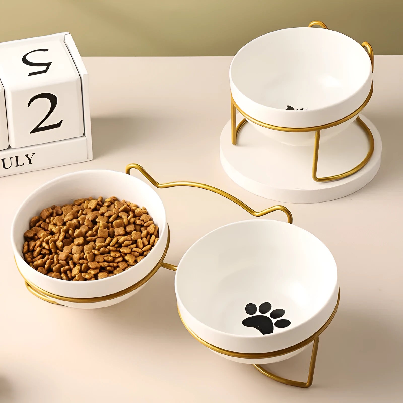 White ceramic cat food bowl with cat paw print design on black iron frame stand