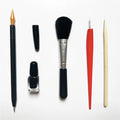 Scratch painting repair tool kit showing scratching pen, repair solution bottle, brushes, and bamboo sticks on a craft table.