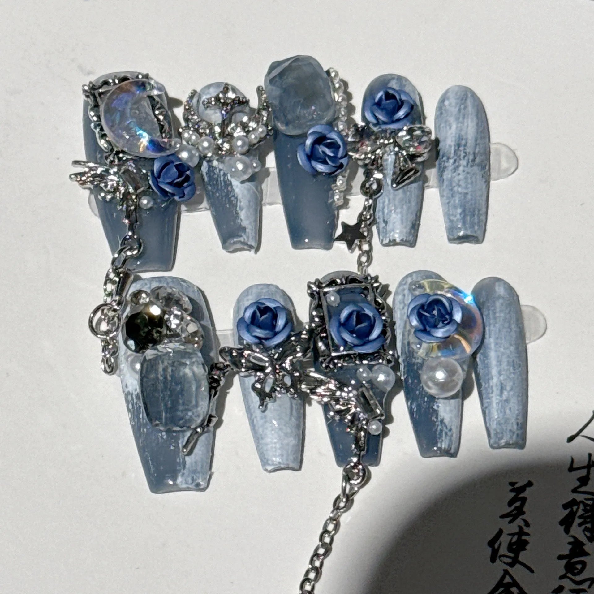 Heavy industry blue manicure nails with rose and tulip floral patterns in plastic armour suit packaging