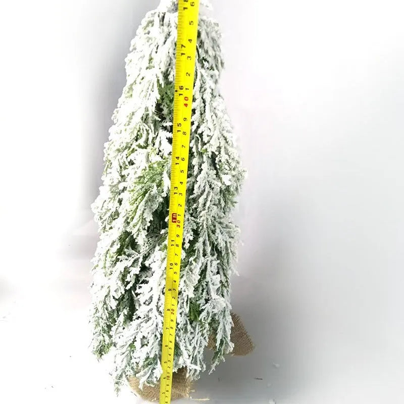 Small 24-inch white artificial Christmas tree with built-in LED lights and simulated snow sprayer on a desktop.