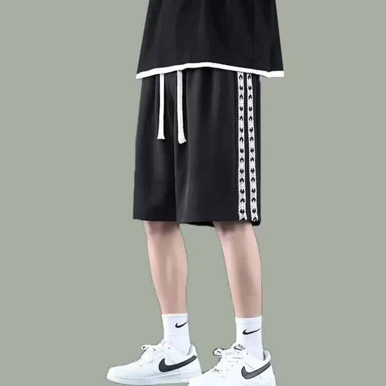 Man wearing loose-fit black track pants made from polyester with a micro-elastic fabric.