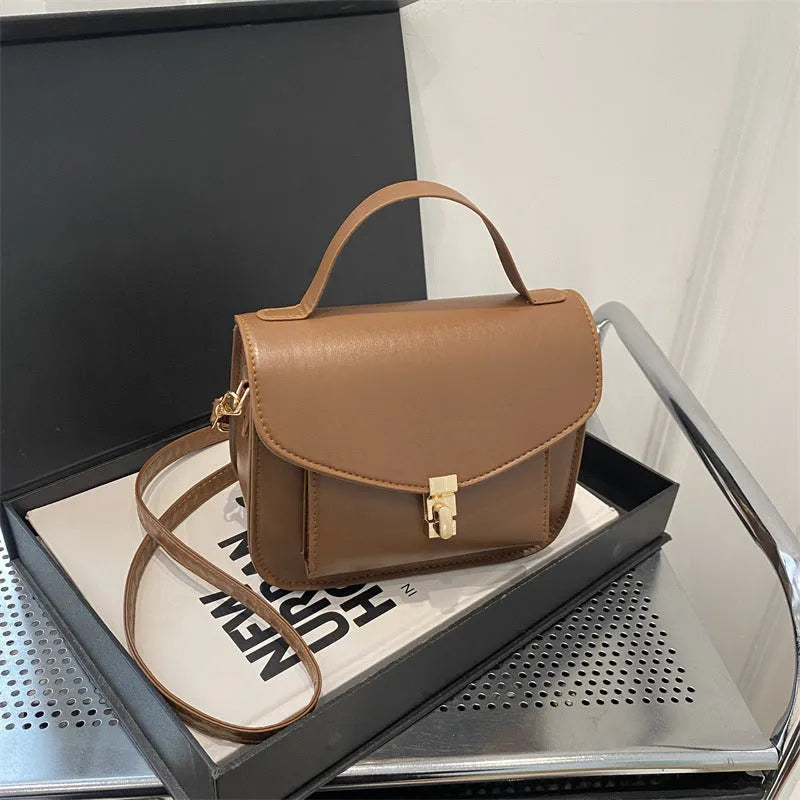 Horizontal square black PU messenger bag with a front sandwich pocket and visible sewing lines.