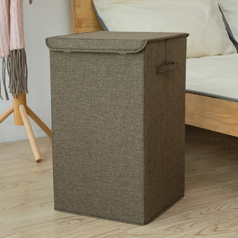Grey foldable cotton linen storage basket shown next to a folded towel and a book.