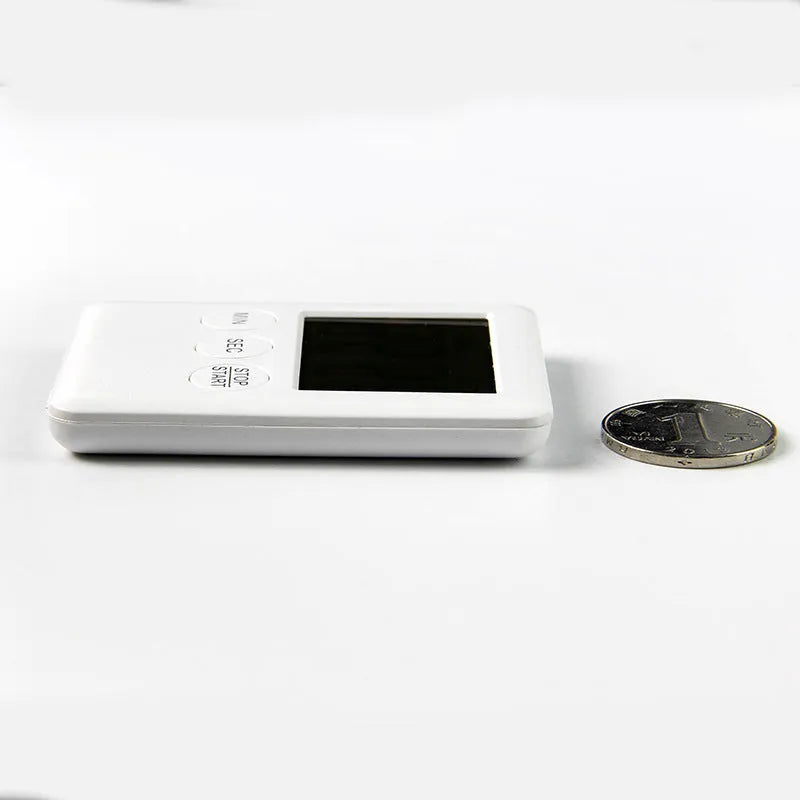 Black and white digital kitchen timer with magnetic back on a refrigerator.