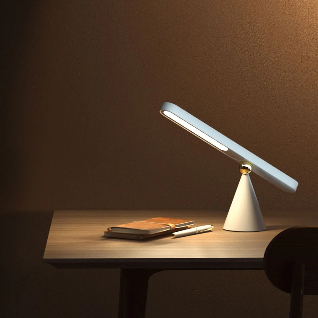 White geometric desk lamp with USB cable and magnetic base for wall mounting.