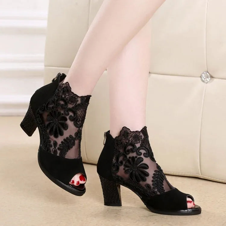 Women's black gladiator sandals with square heels and flower lace upper showing zip closure detail