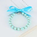 Small dog wearing adjustable pearl necklace with rhinestones and ribbon bow decorative collar