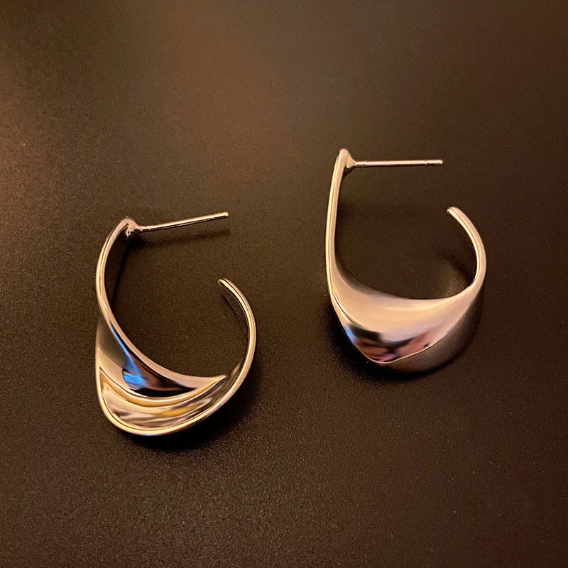 Metal twisted geometric earrings with electroplated gold or silver finish showing round design elements