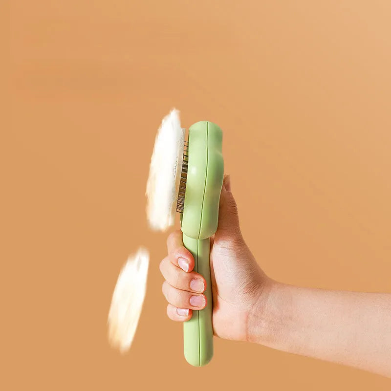 Green self-cleaning stainless steel pet comb with removable needle head on a white background.