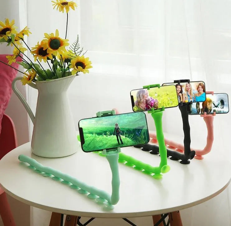 Black flexible arm phone holder with suction cup base bent into an S-shape, holding a mobile phone.