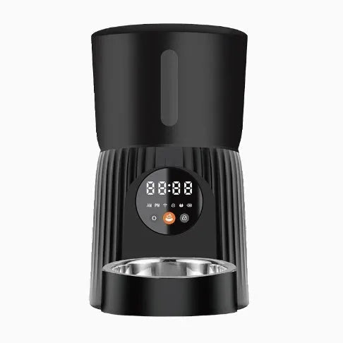 Black automatic pet feeder with digital display and food hopper on a countertop.