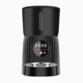 Black automatic pet feeder with digital display and food hopper on a countertop.