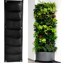 Green recycled felt vertical wall planter with multiple pockets hung on an outdoor fence.