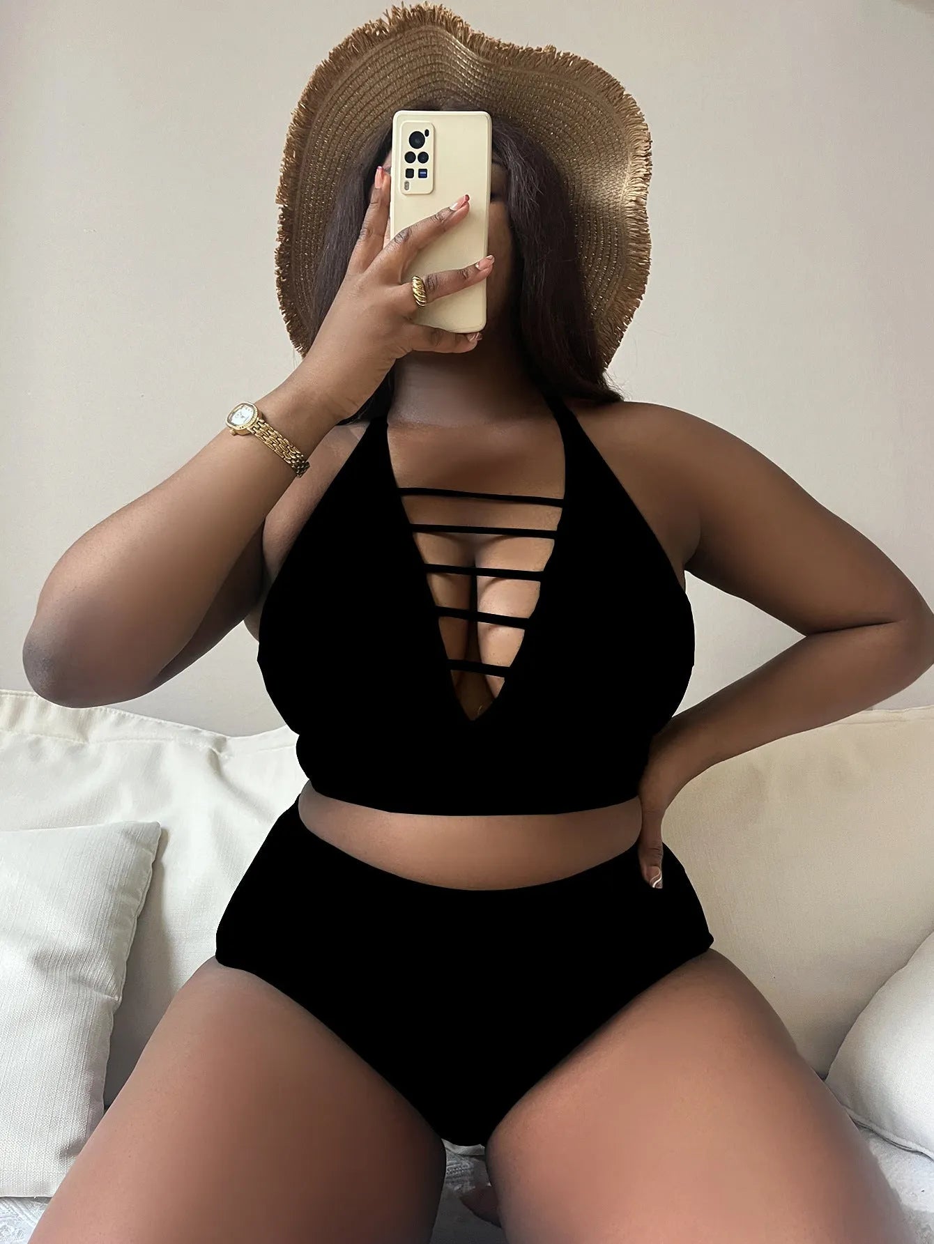 Plus size woman in a black halter bikini with cross-back straps and high-waist briefs on the beach.