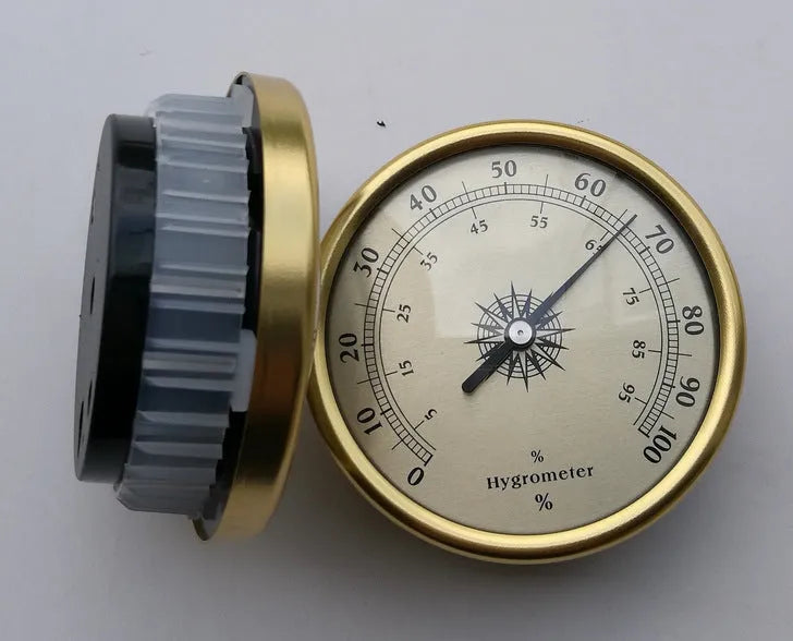 Analog thermometer and hygrometer with silver aluminum outer ring and dial on a white background