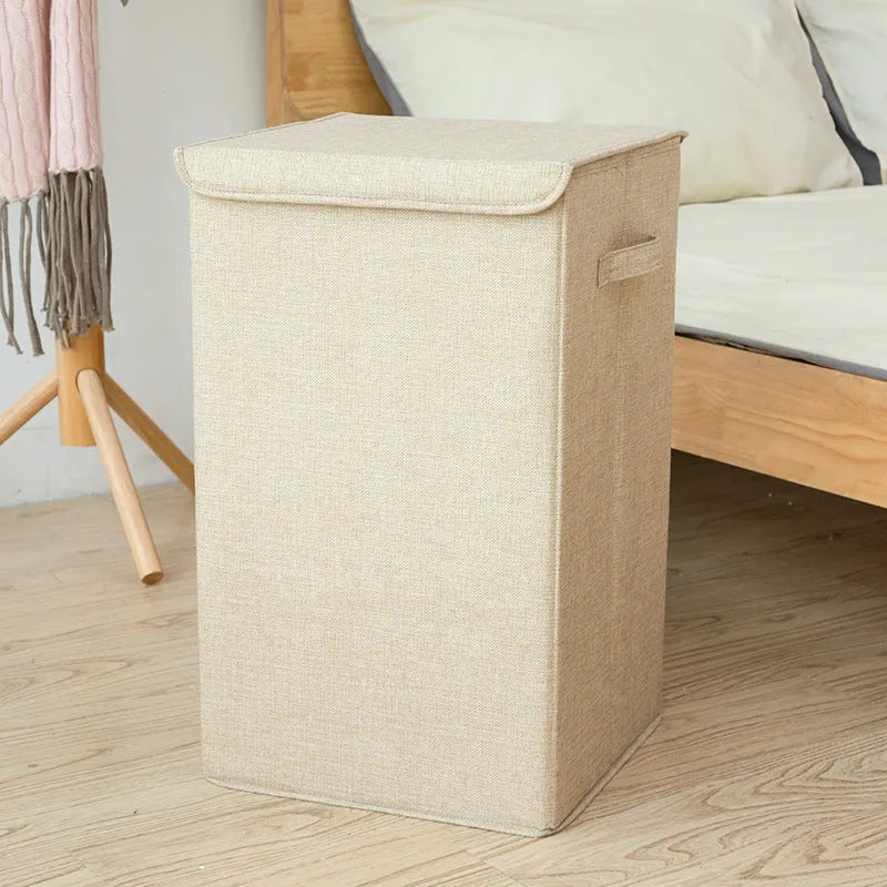 Grey foldable cotton linen storage basket shown next to a folded towel and a book.