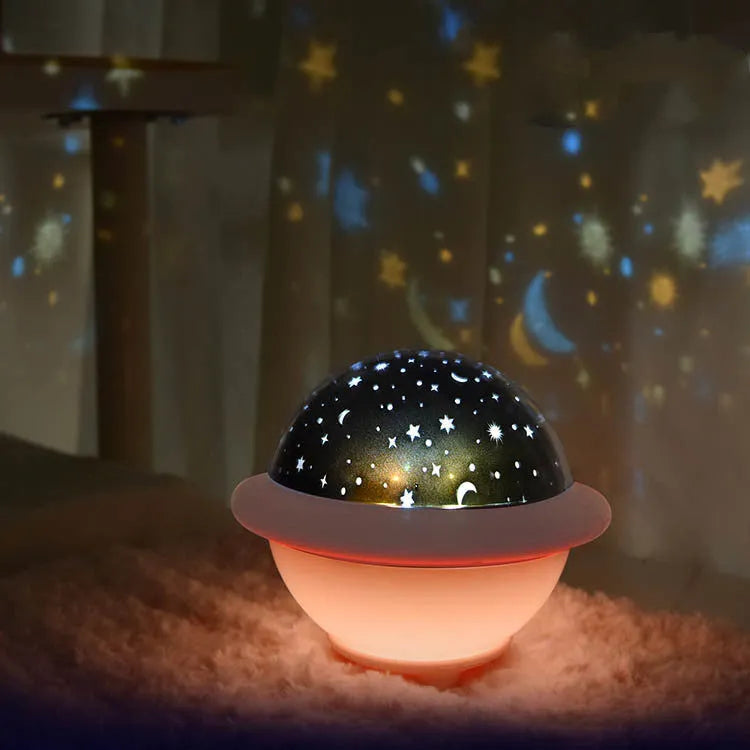 Pink UFO-shaped plastic LED night light projecting a starry sky pattern on a wall.