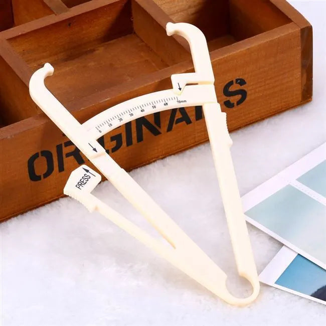 Clear acrylic body fat caliper skin fold thickness meter showing measurement scale