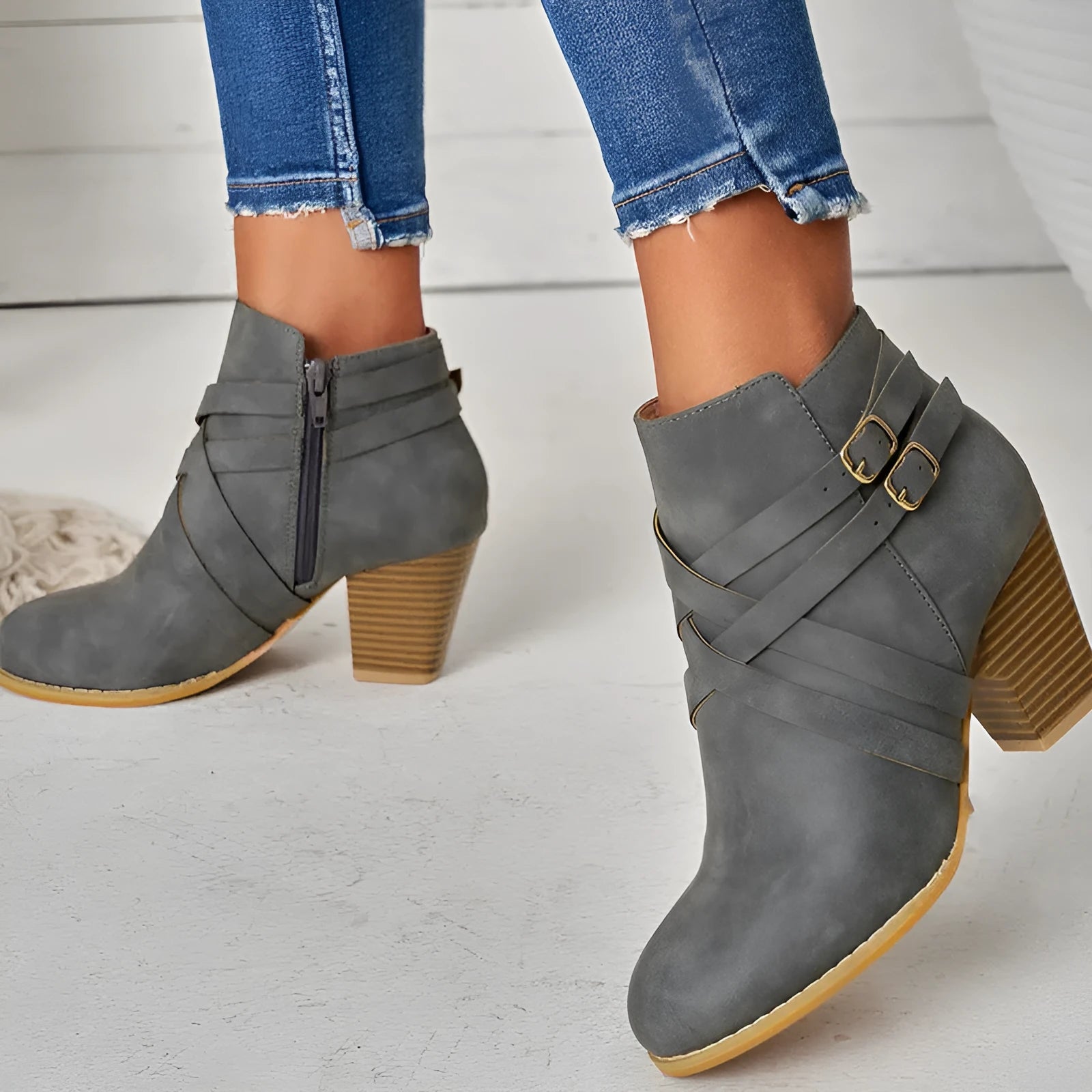 Grey plus-size short boot with 7cm heel, side zip, and buckle detail on a wooden floor