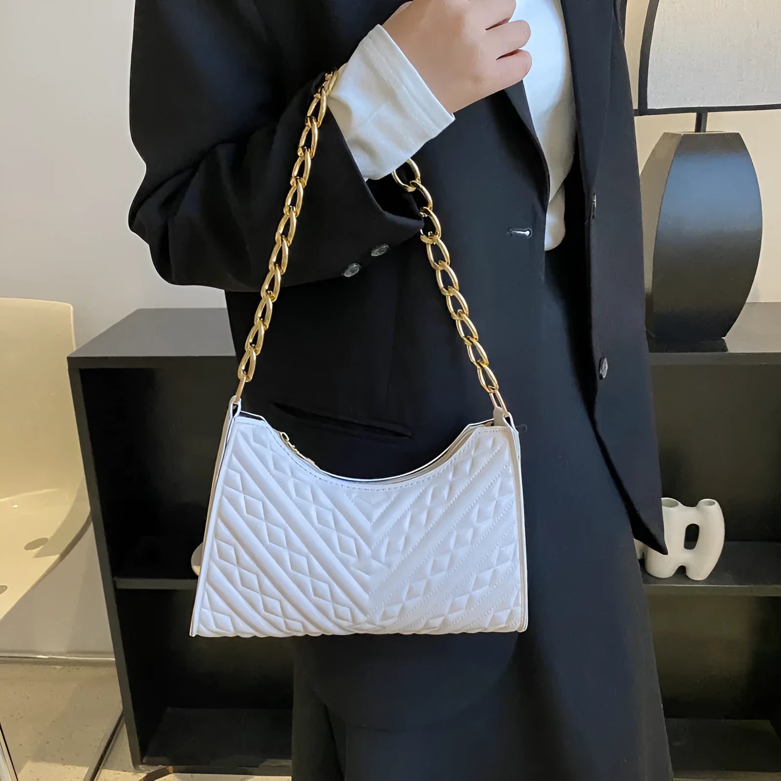 Brown pleated chain baguette women's shoulder bag with adjustable strap on a mannequin.